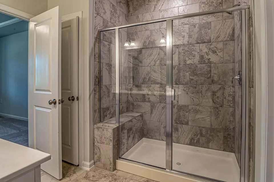 Frameless glass shower enclosure in a marble-tiled bathroom