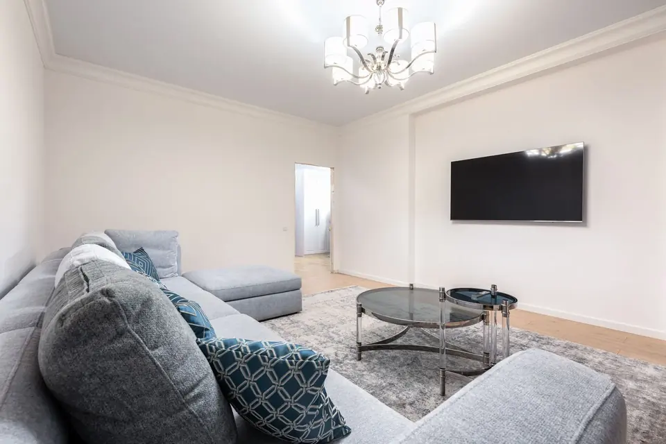 Contemporary room with sofa and TV beneath a chandelier