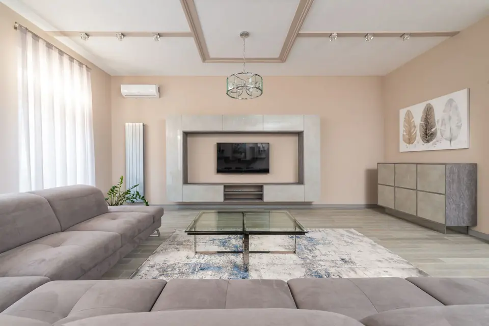Modern living room with glass table, sofa, and wall-mounted TV