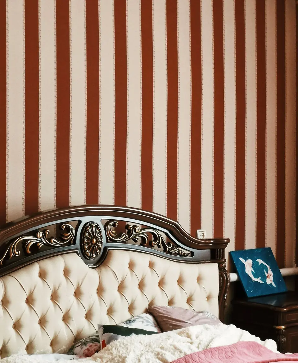Luxurious bedroom with carved wooden headboard and striped wallpaper